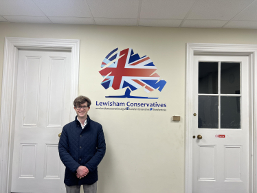 Hugh Rees-Beaumont standing next to a Lewisham Conservatives sign.